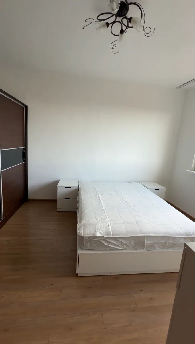 Bedroom with light-colored walls, a bed and a wardrobe